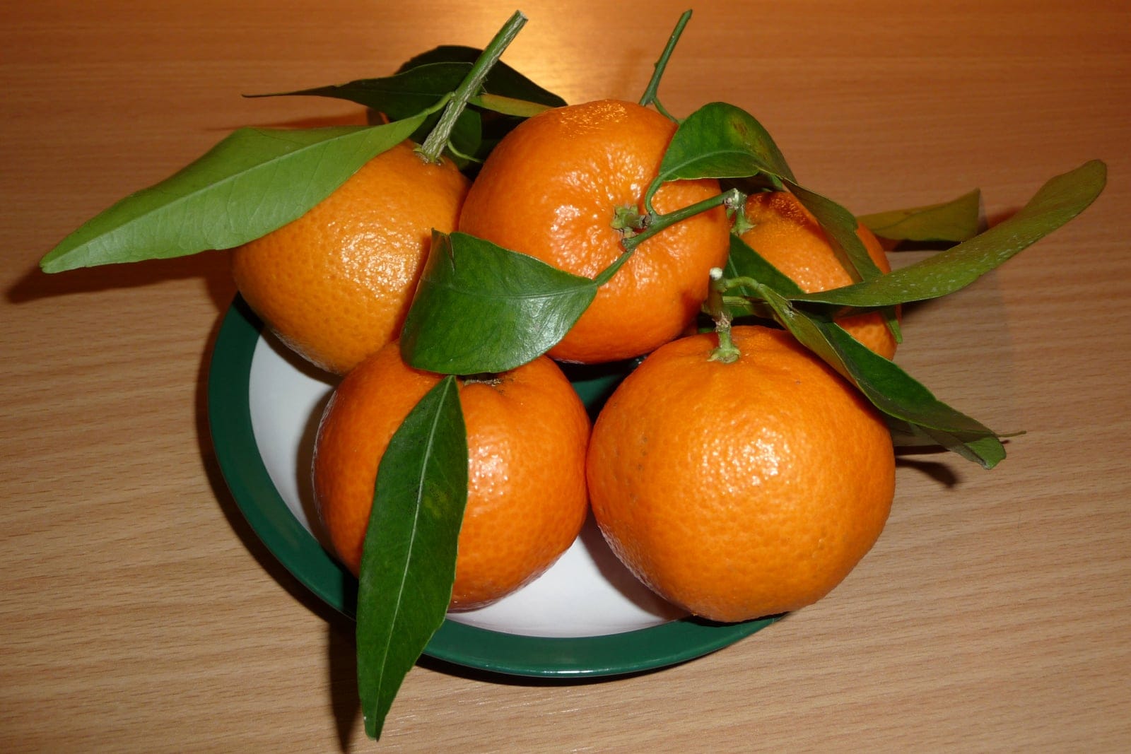 Several whole ripe mandarin oranges, showing the characteristic flattened orange fruit with dimpled glossy peel