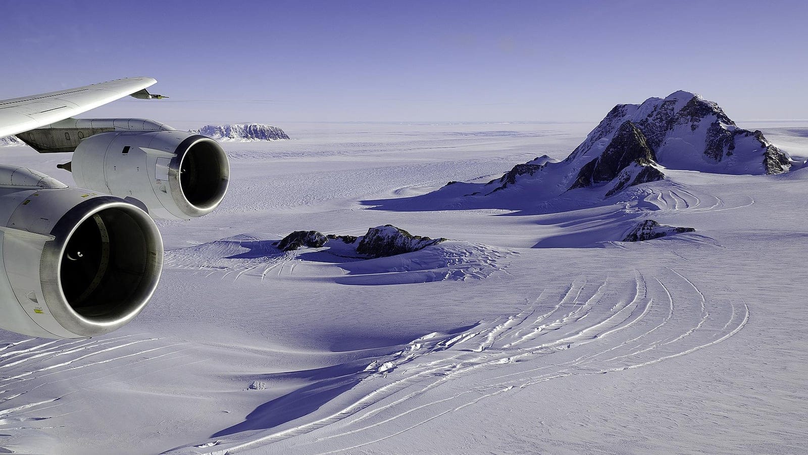 Aircraft engines framing crevassed snowfields and rock nunataks over Marie Byrd Land, West Antarctica.