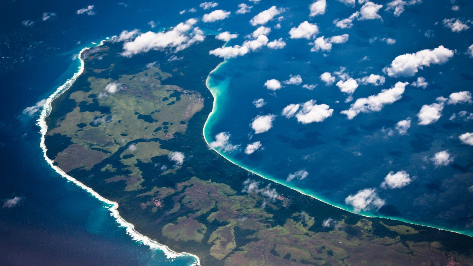 Forêt, clairières et un littoral frangé de vagues sur l'île de Teressa, îles Nicobar, vus de haute altitude.