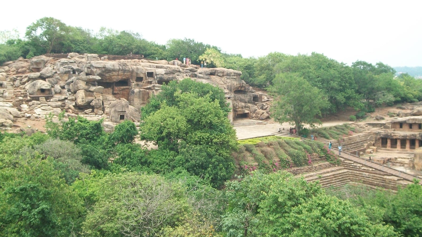 Rock-cut cave galleries and stepped terraces among broadleaf trees at Udayagiri and Khandagiri, Odisha.