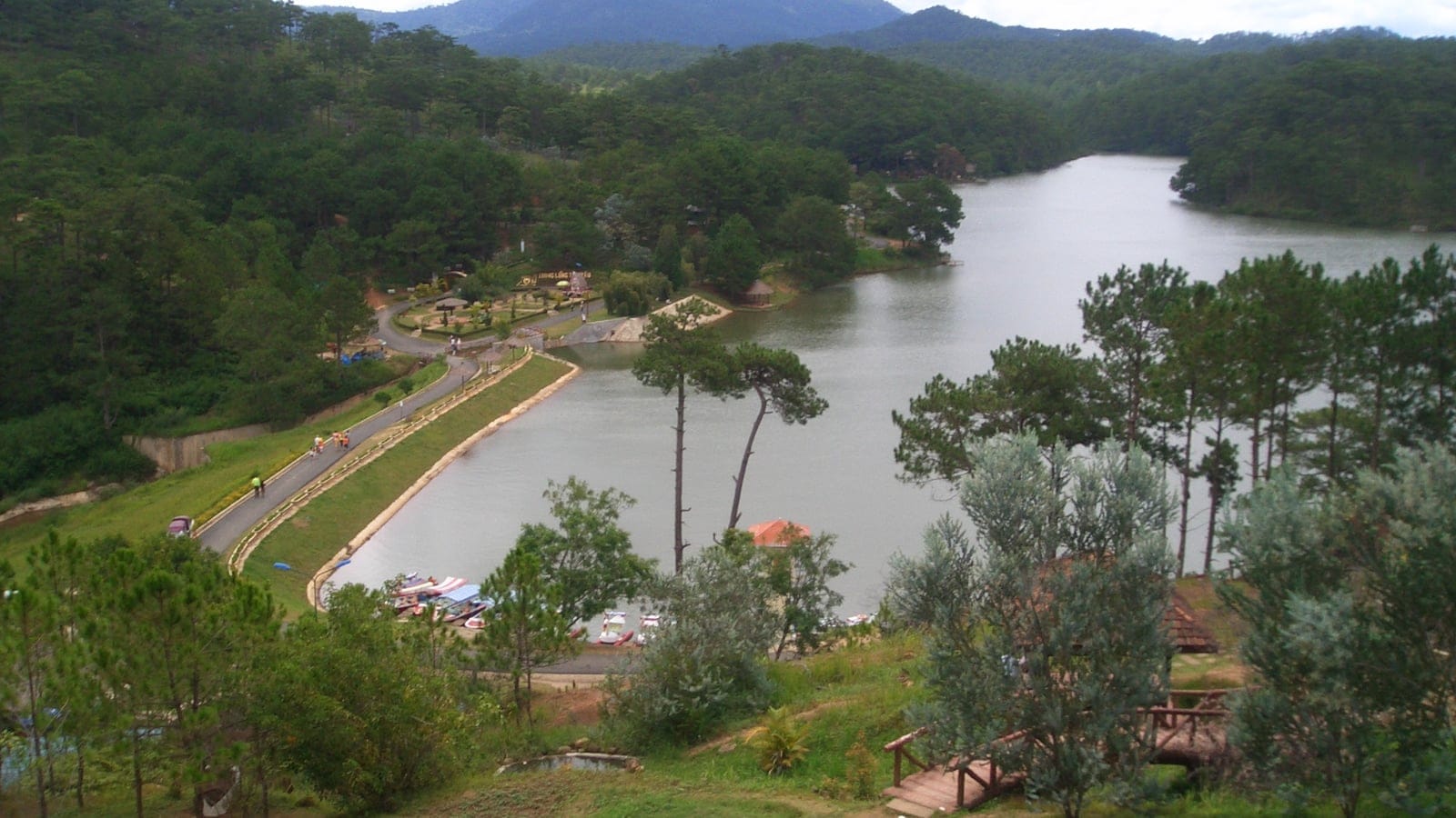 Planted pine slopes around the landscaped Valley of Love reservoir with pedal boats, Da Lat, Vietnam.