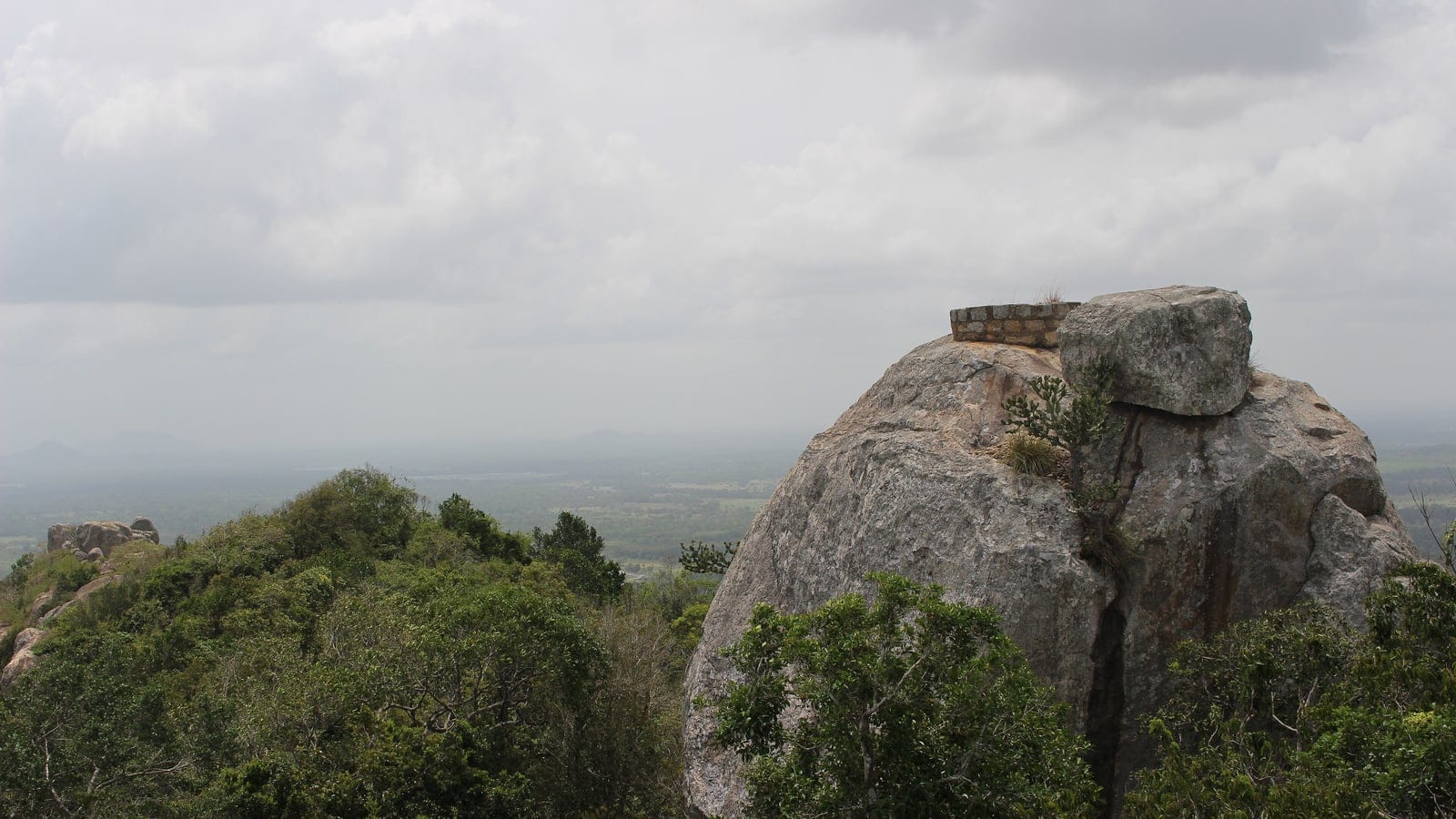 Granite dome and dry evergreen forest canopy above a hazy lowland plain near Anuradhapura, Sri Lanka.