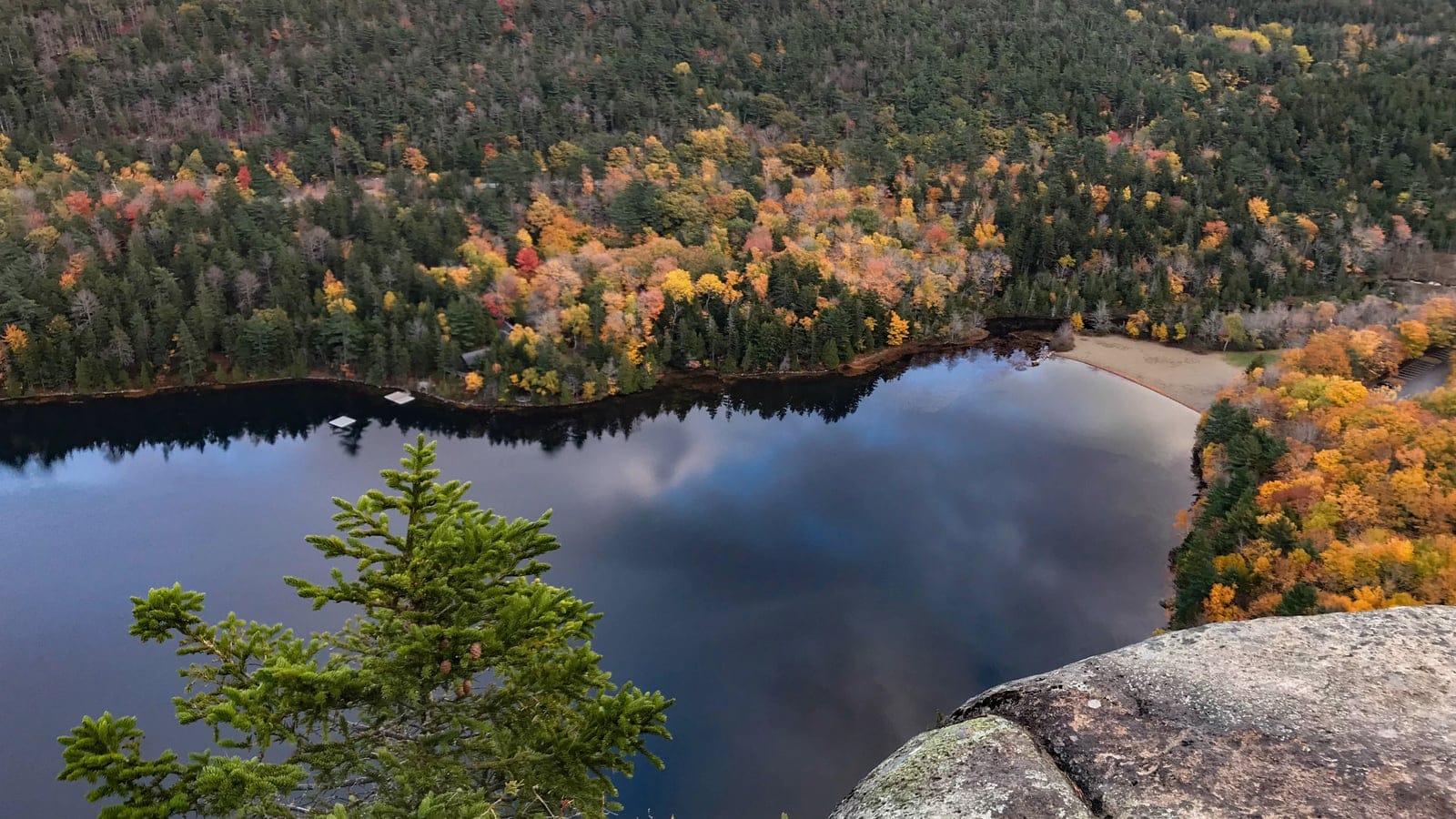 Echo Lake seen from the Beech Cliff Trail in Acadia National Park, Maine, with mixed forest cloaking the surrounding hillslopes in autumn color above the lakeshore.