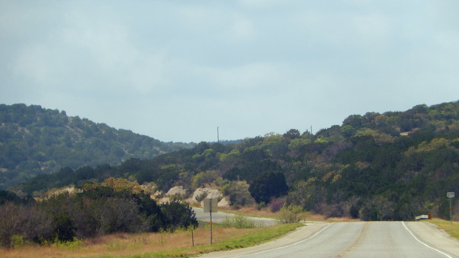 Juniper and oak brush on limestone hills above a highway north of Del Rio, Texas.