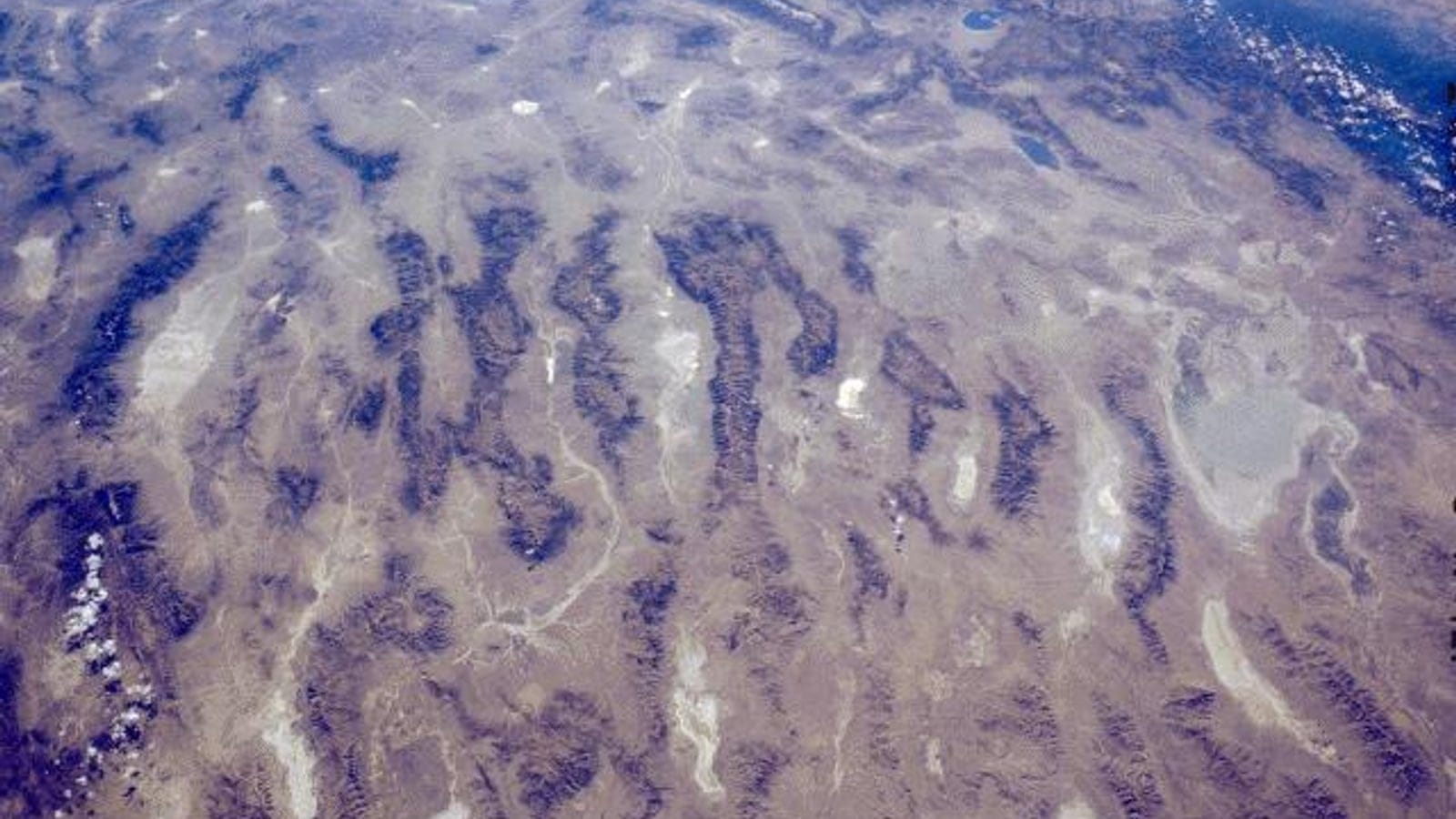 Oblique orbital view of parallel fault block ranges and pale basin floors in central Nevada.