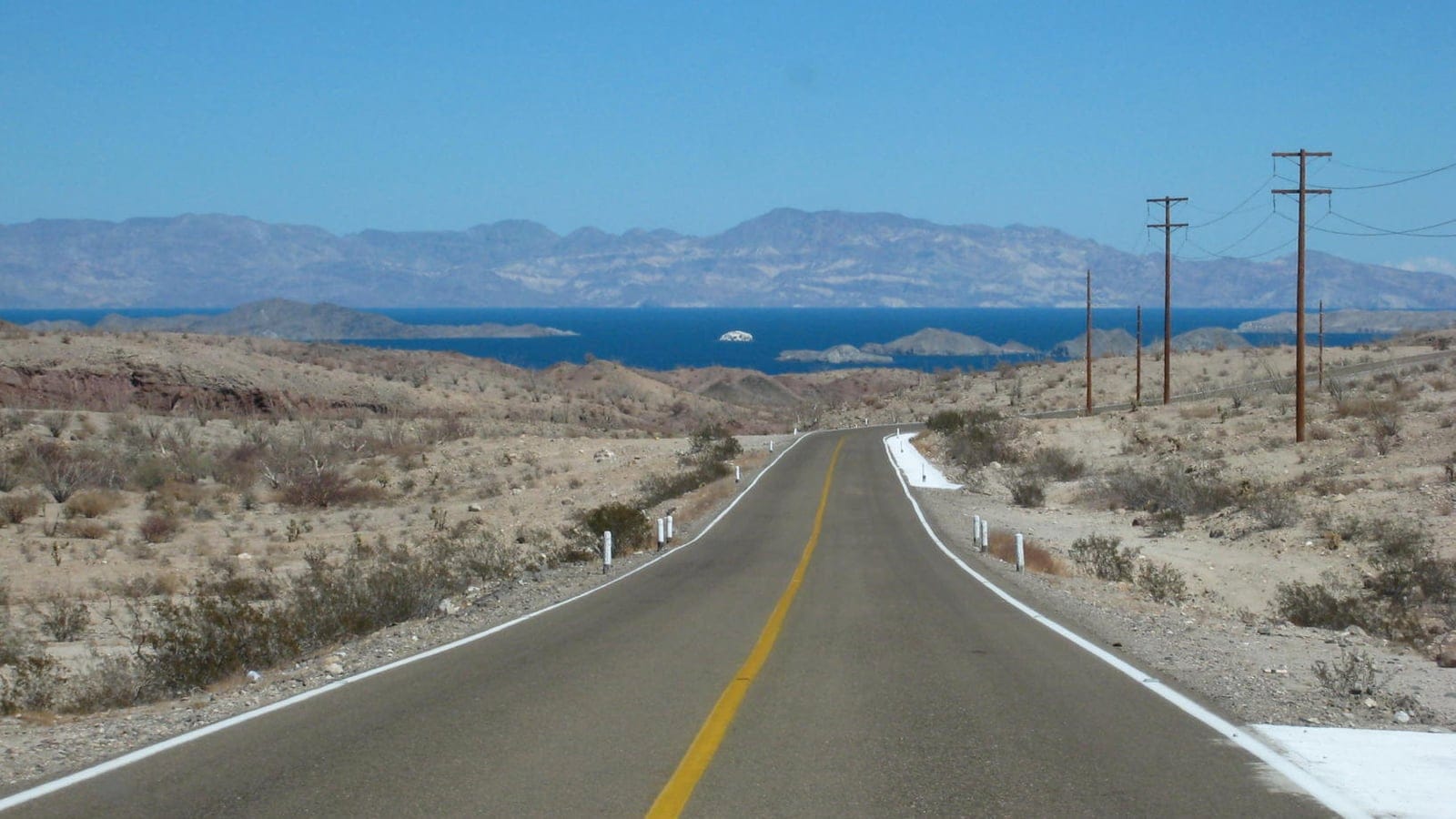 Highway running down through sparse desert scrub to the Sea of Cortez, Baja California, Mexico.