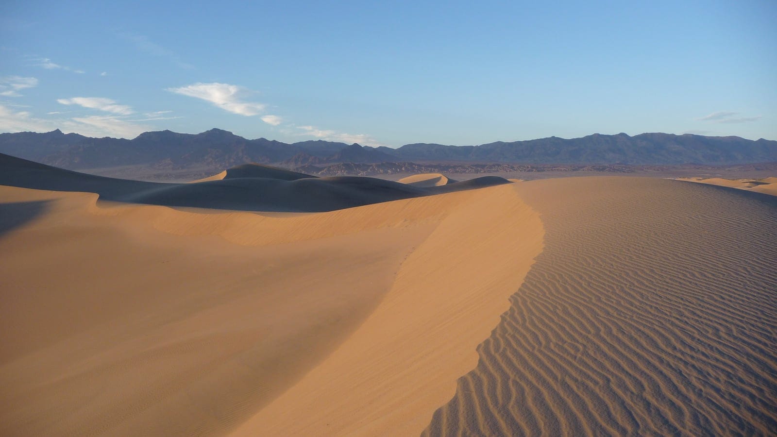 Rippled bare sand dunes below barren ranges at Mesquite Flat, Death Valley, California.