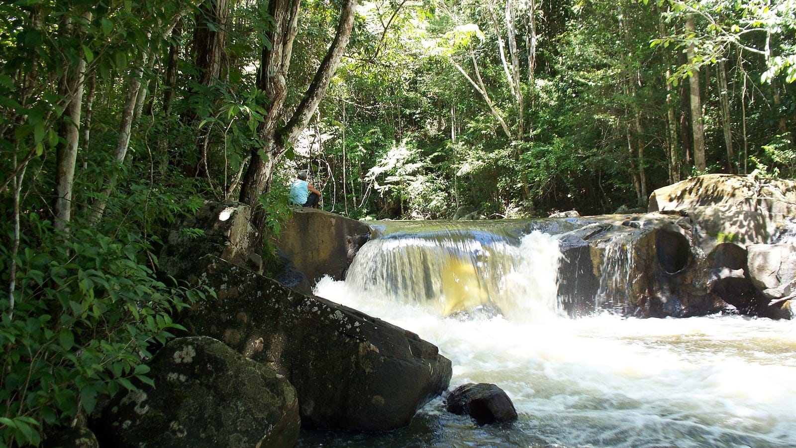 Forest-lined waterfall over rock ledges near Paramakatoi, Guyana.