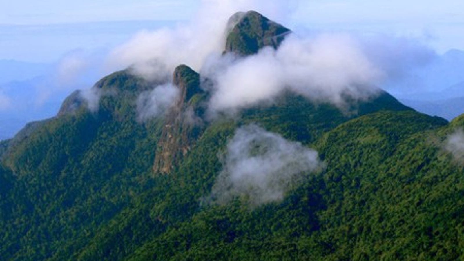 Nuages se déversant sur des crêtes de forêt tropicale humide et un éperon de granite nu à la Serra da Mocidade, Roraima, Brésil.