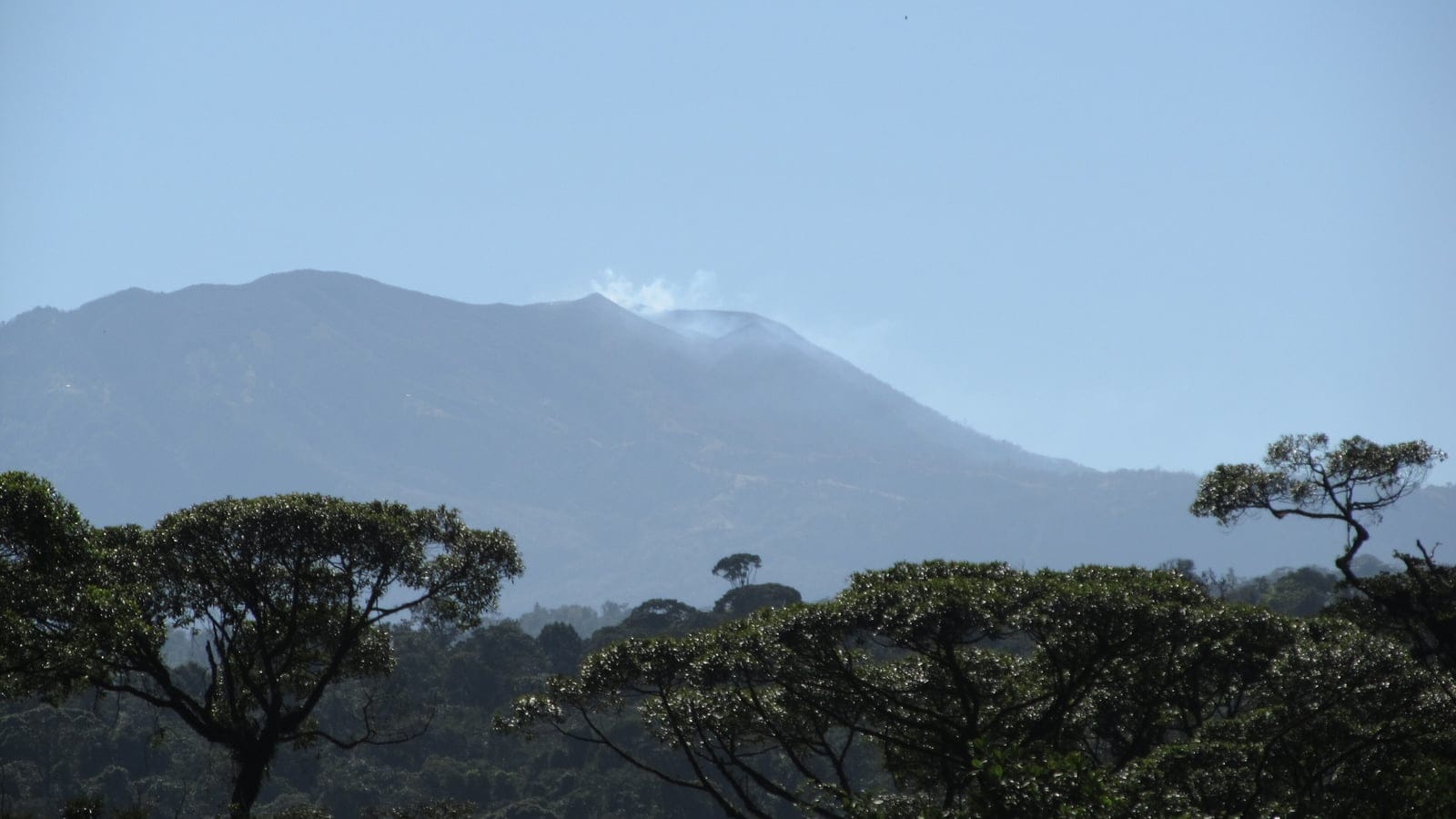 Steaming summit of Volcan Turrialba above a distant forest canopy, Costa Rica.