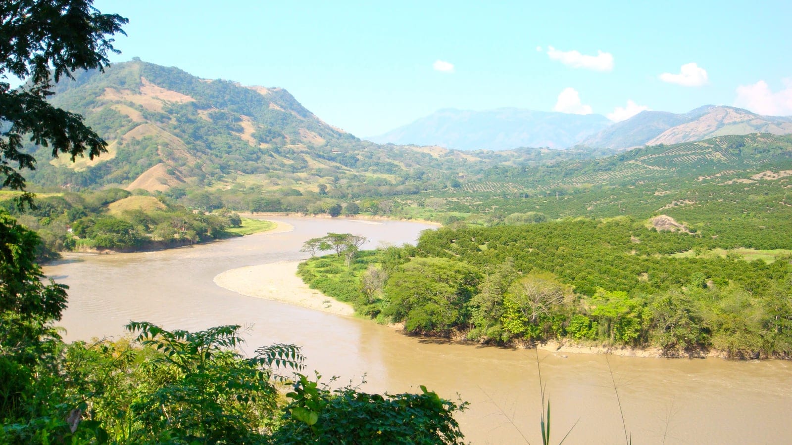 The Cauca River winding between dry hills and riparian scrub near Tarso, Antioquia, Colombia.
