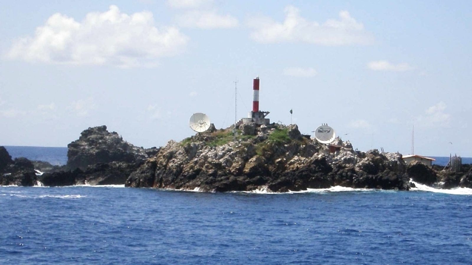 Guano-stained rocks with a lighthouse and dish antennas, Saint Peter and Saint Paul Rocks, Brazil.