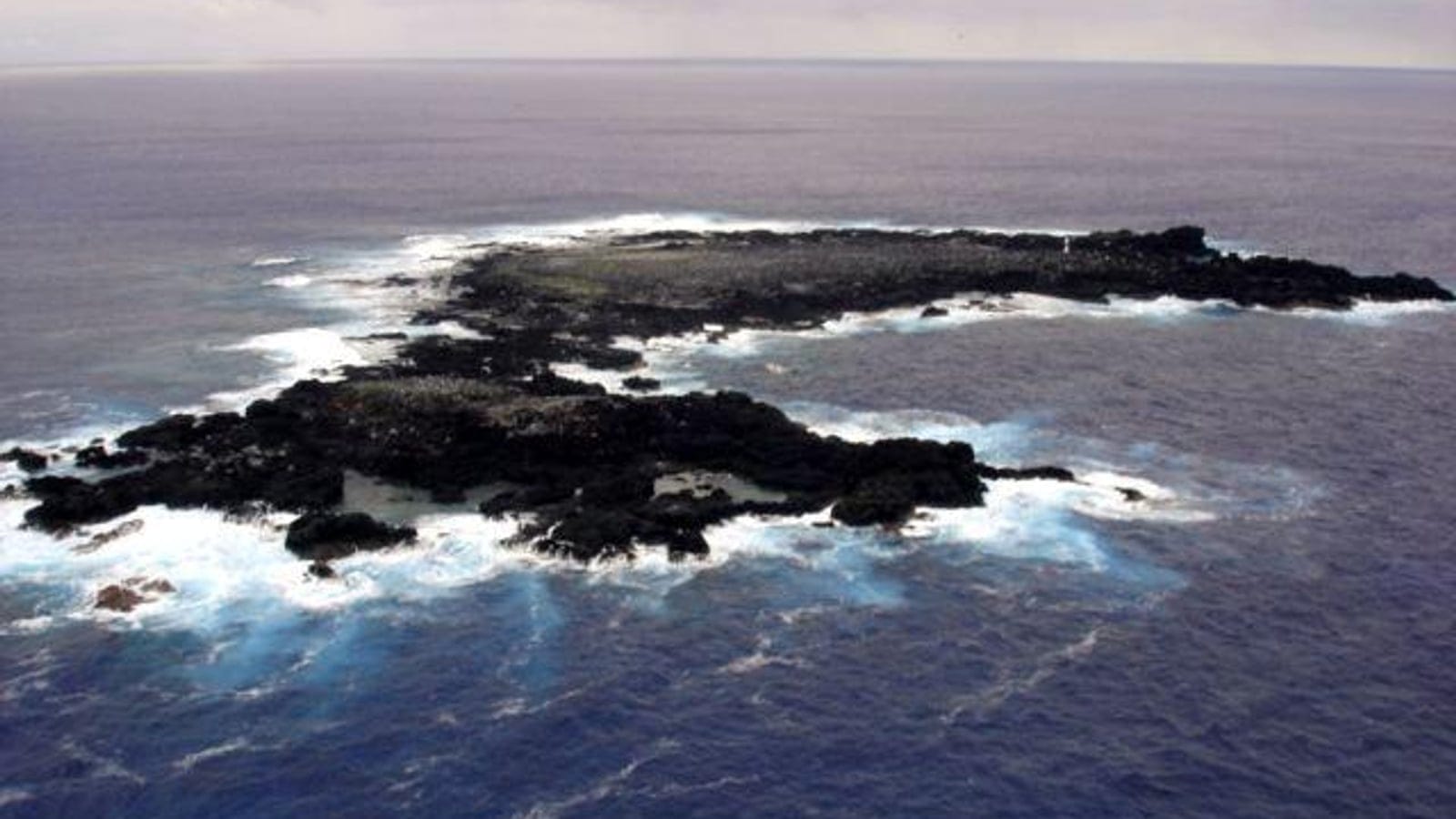 Aerial view of the bare basalt platform of Sala y Gomez ringed by breaking surf, Chile.