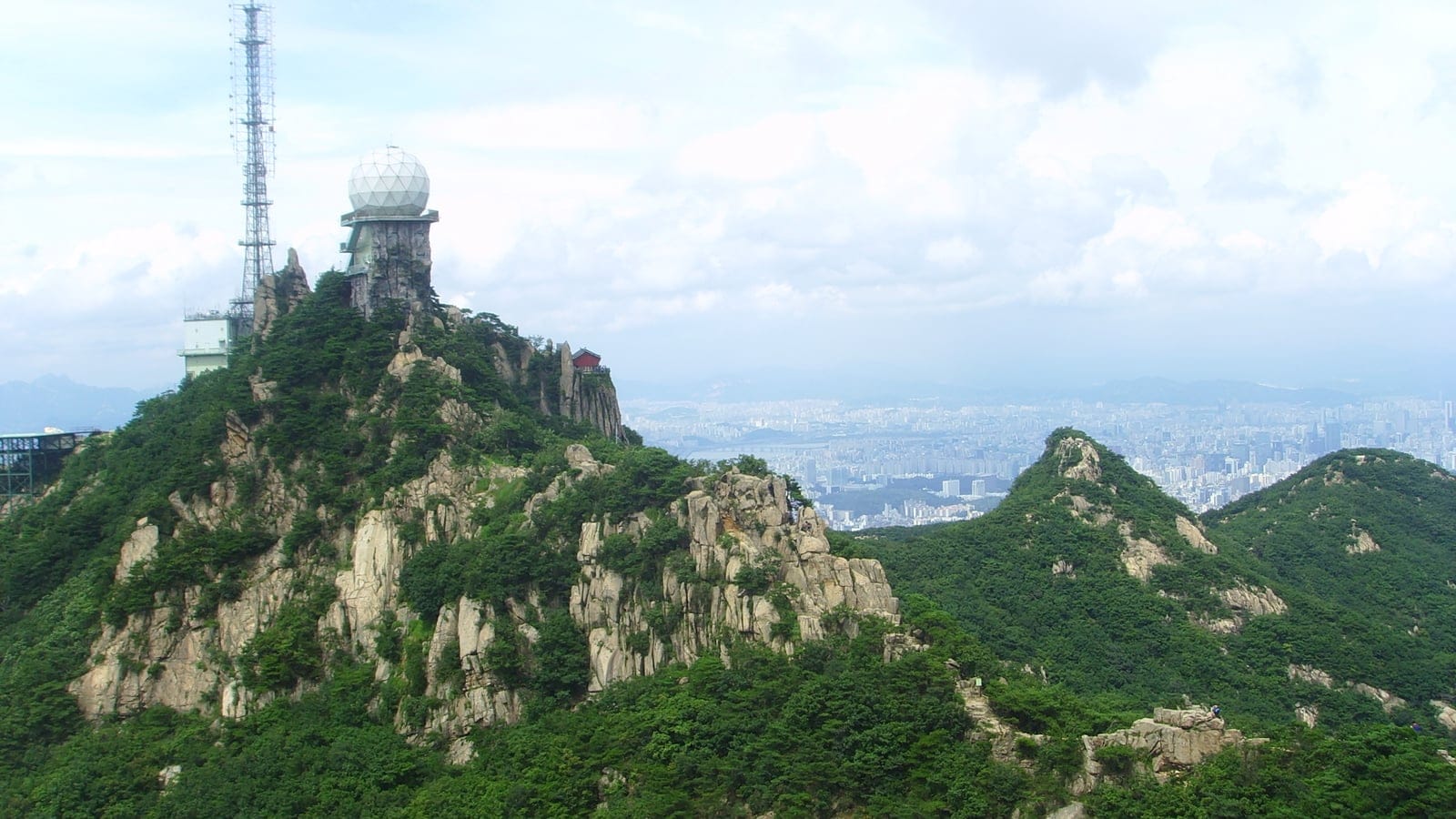 Granite crags, a radar dome and pine scrub on Gwanaksan above the Seoul skyline, South Korea.