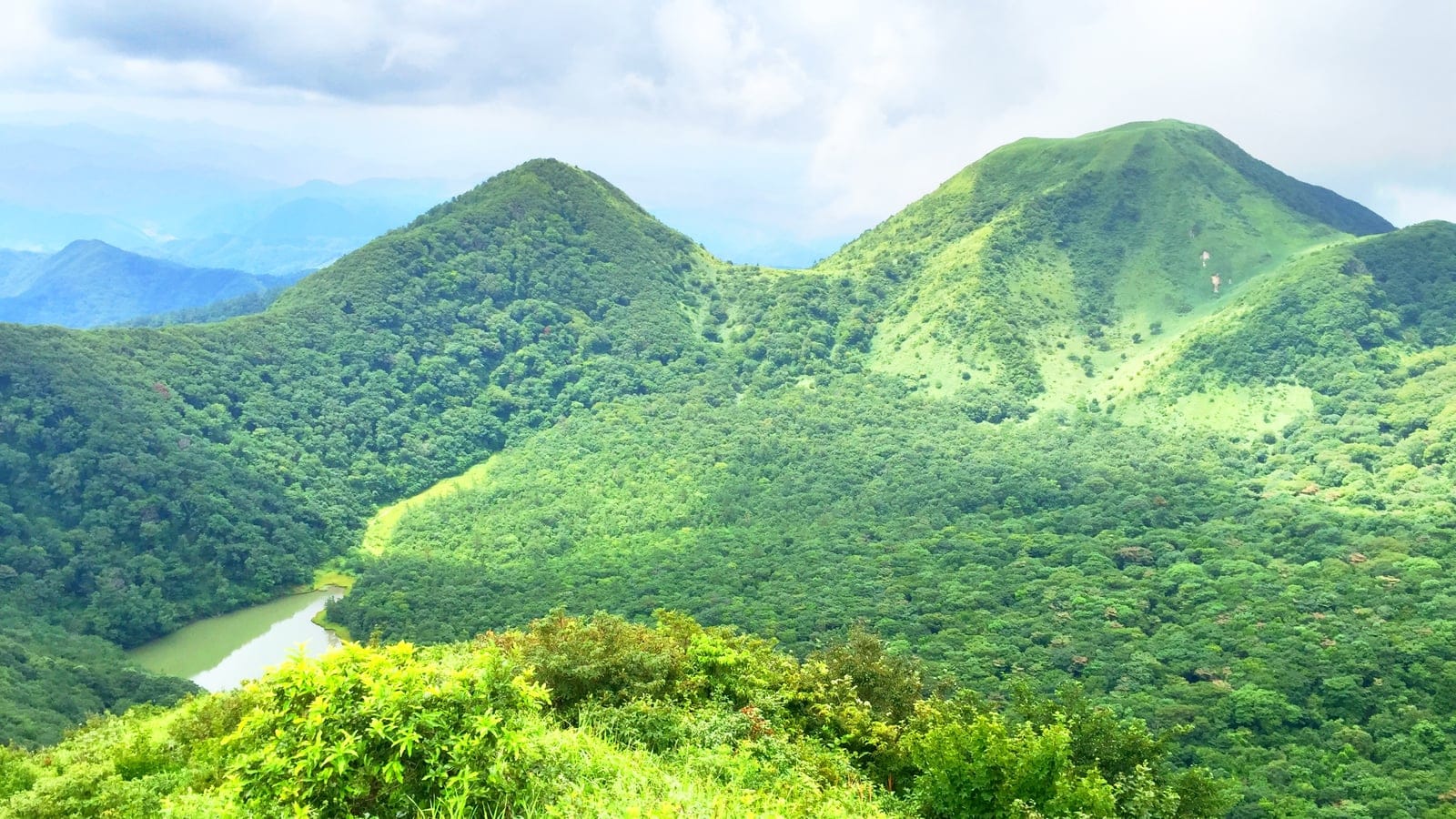 Forested cones and grassy slopes around a reservoir at Mount Sanbe, Shimane, Japan.