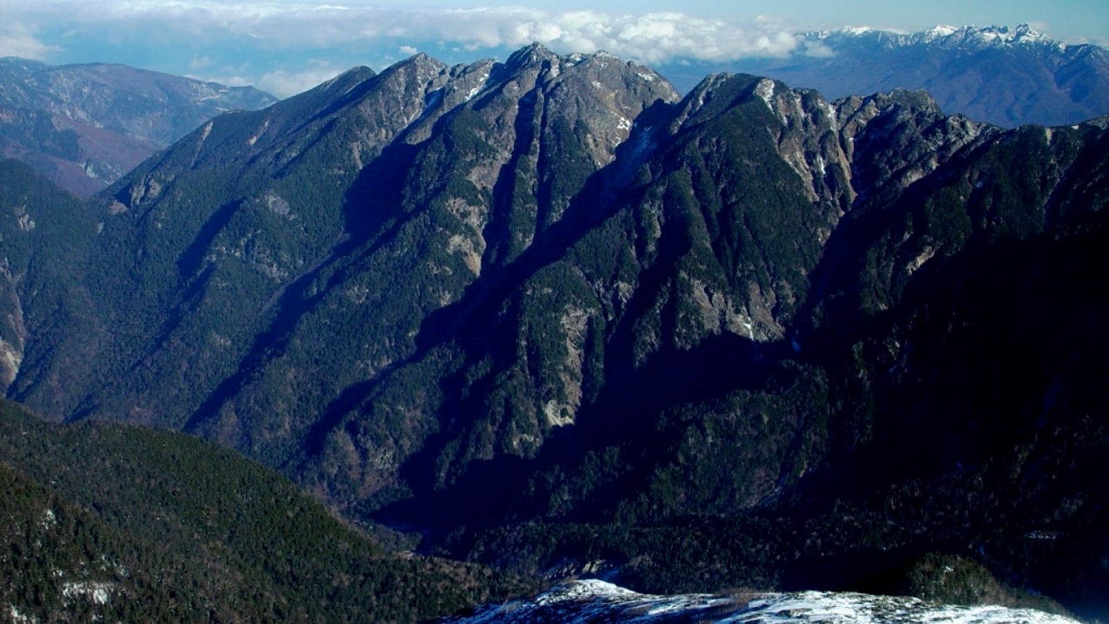 Steep forested ridges and snow-streaked crags seen from Kosenjo toward Mount Nokogiri, Japan.
