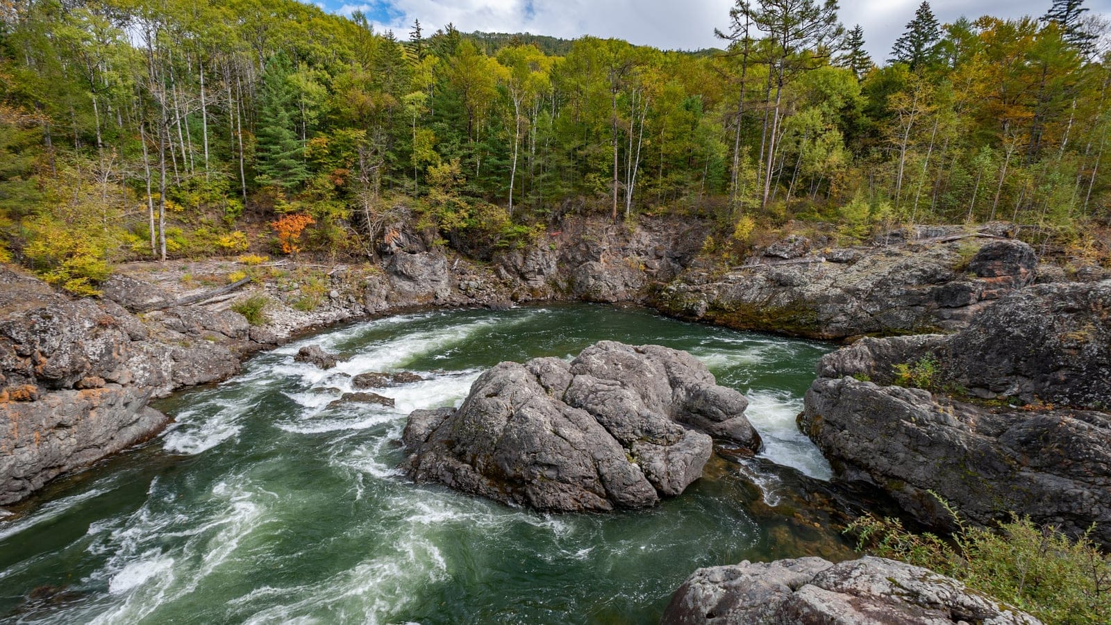 Rapids splitting around a midstream boulder below birch, aspen and spruce forest on the Kema River, Russian Far East.