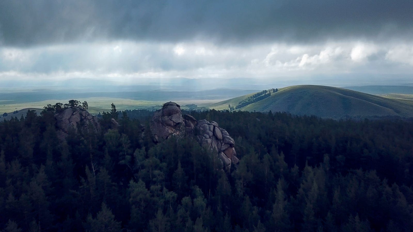 Rocky woodland and steppe terrain in Karkaraly National Park, Kazakhstan.