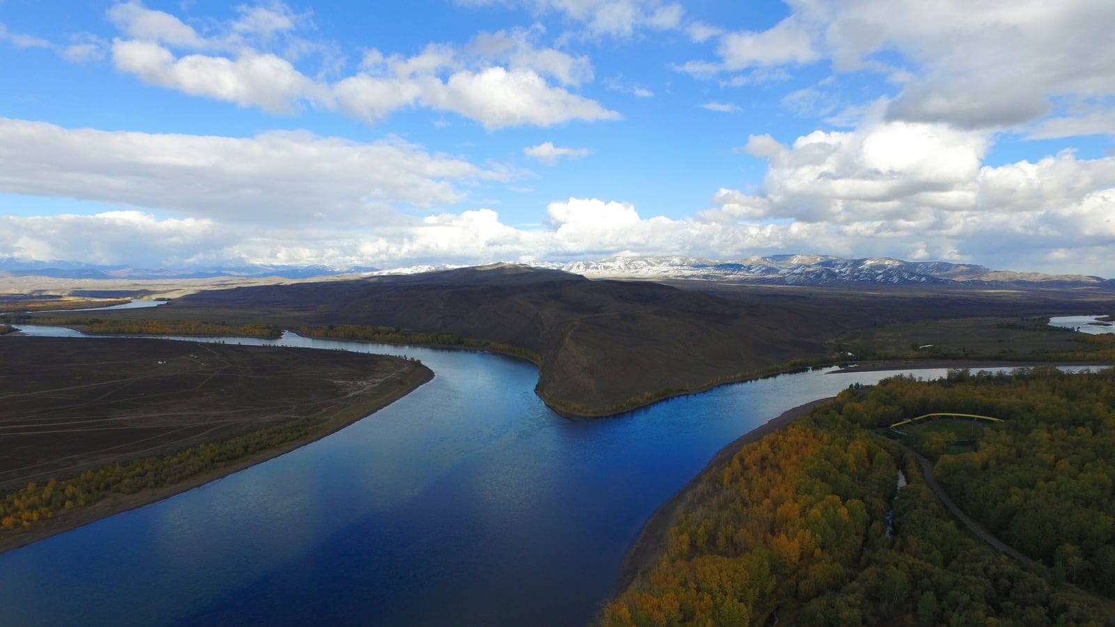 Golden riparian woodland and bare steppe hills at the Yenisei confluence, Sayan region, Russia.