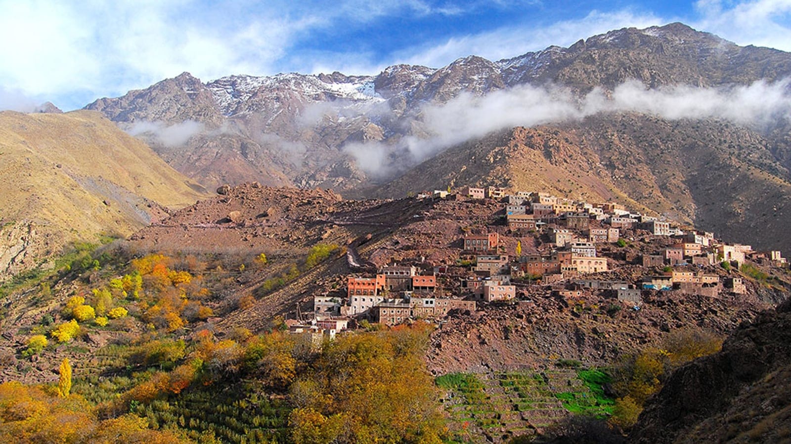 Terraced plots and autumn walnut and poplar trees below a stone village on the Toubkal slopes, High Atlas, Morocco.