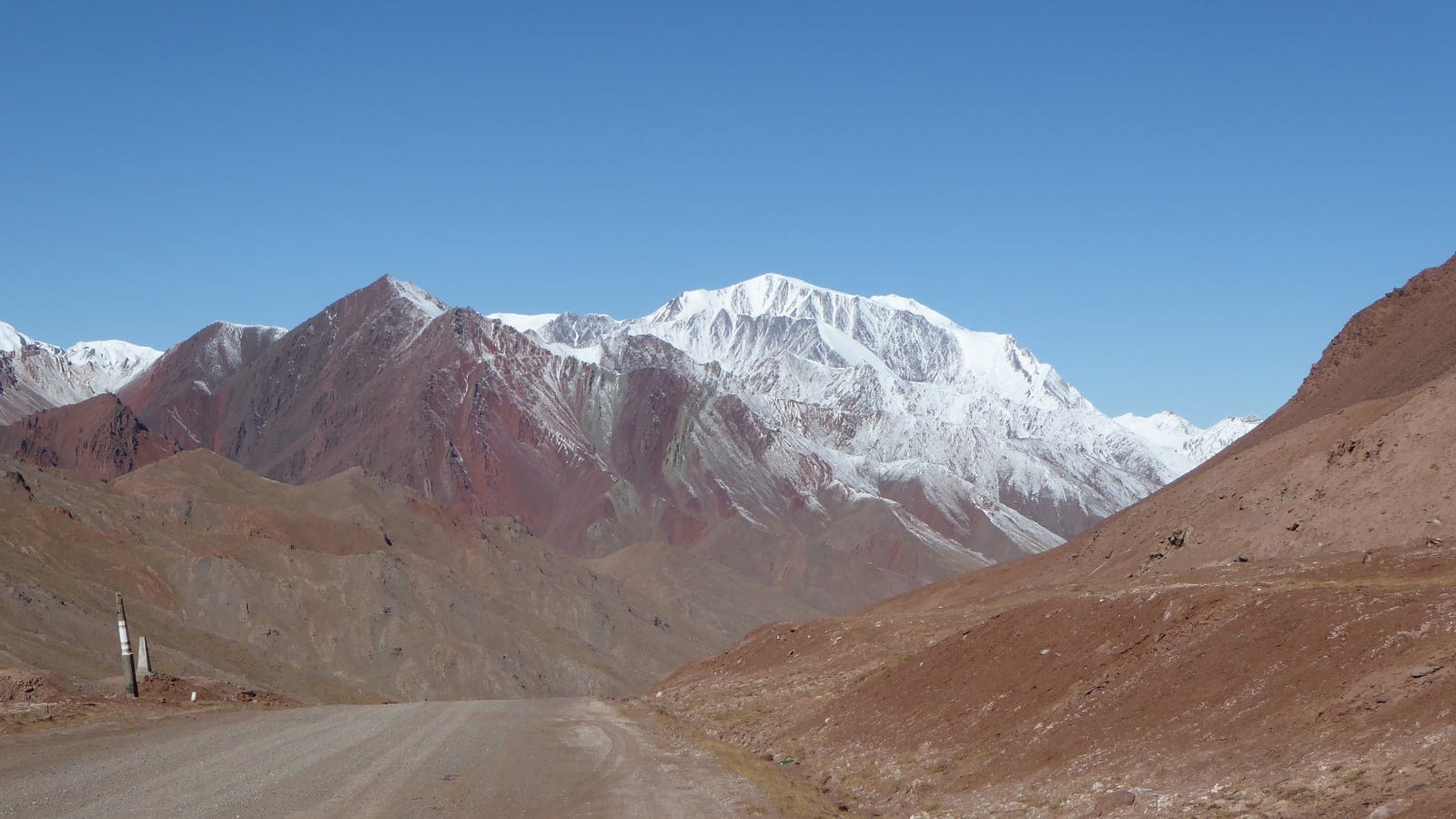 Bare scree slopes and a snow peak above the Pamir Highway.