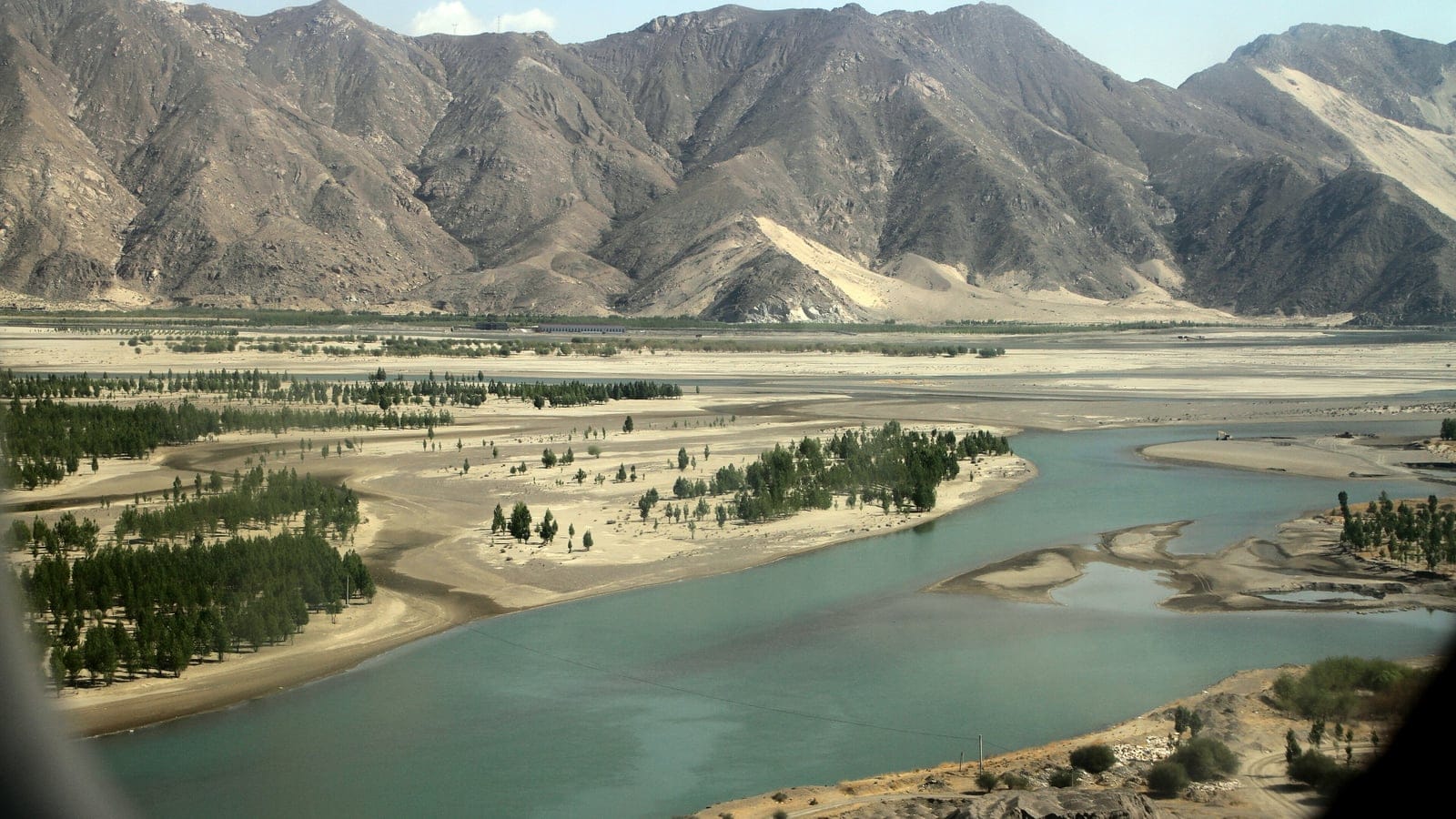 Sandbars and rows of planted poplar along the braided Yarlung Tsangpo below bare eroded ridges, Shannan, Tibet.