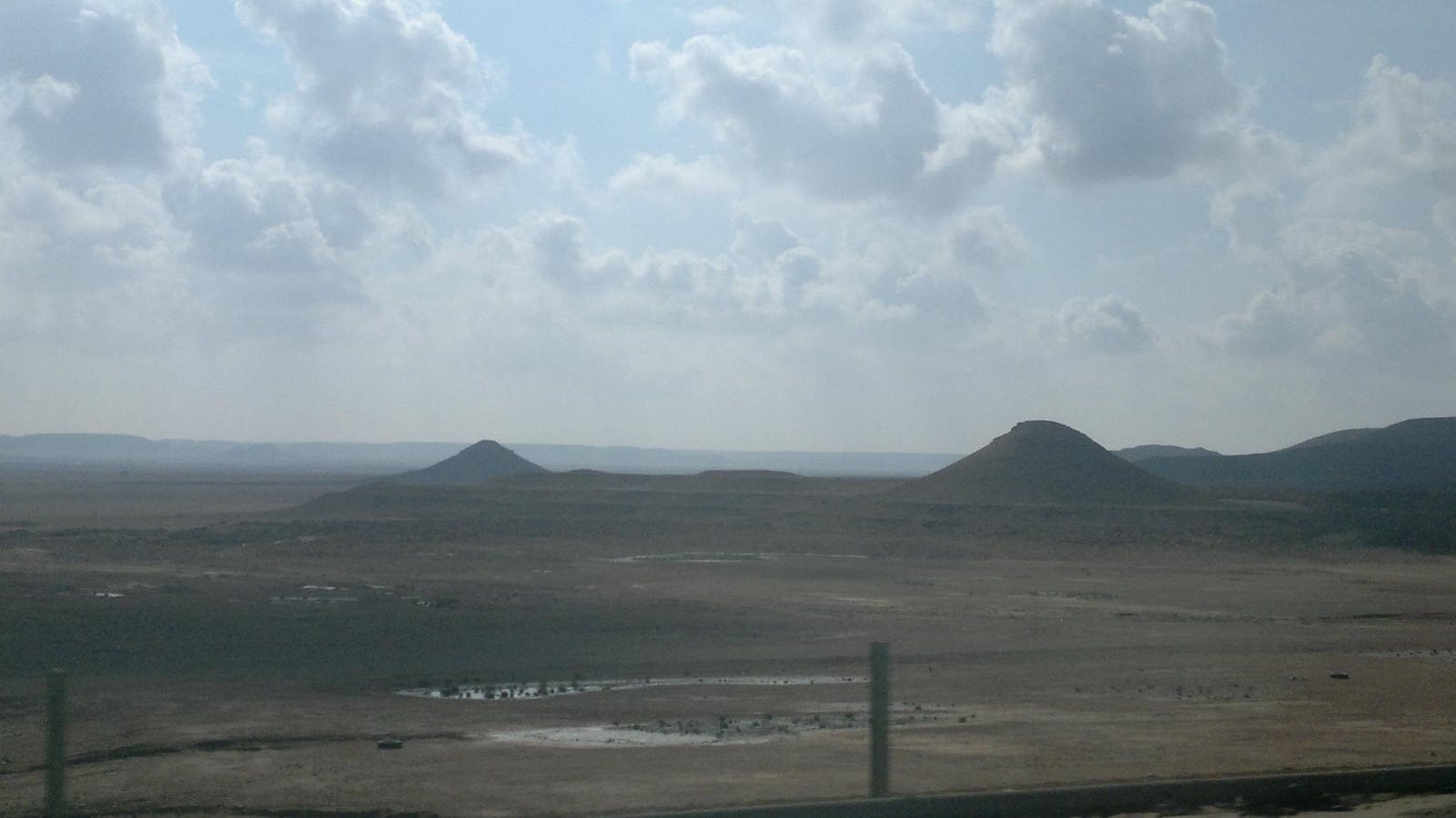 Stony desert plain and low flat-topped mesas under broken cloud near Ar Rutbah, western Iraq.