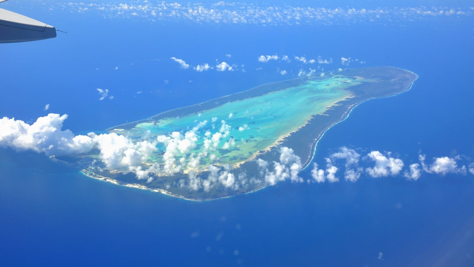 Aldabra Atoll's turquoise lagoon inside a scrub-darkened reef rim, seen from a passing aircraft, Seychelles.