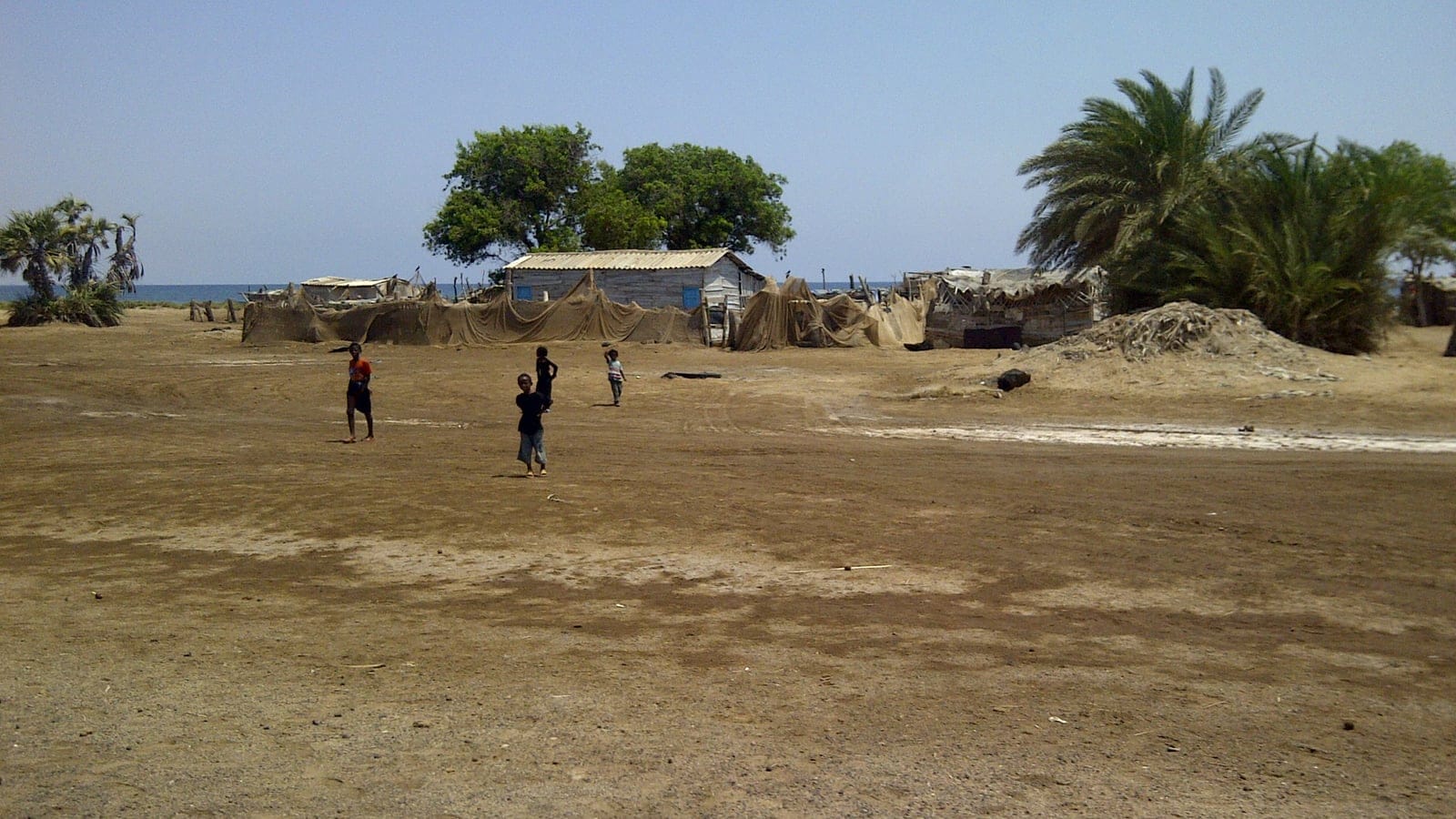 Fishing shacks and drying nets on bare coastal ground at Southern Dankalia, Eritrea.